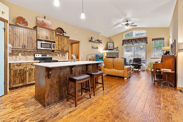 161 Oakmont Loop, Columbia Falls, MT 59912 - kitchen featuring stainless steel appliances, ceiling fan, light wood finished floors, lofted ceiling, and a breakfast bar area