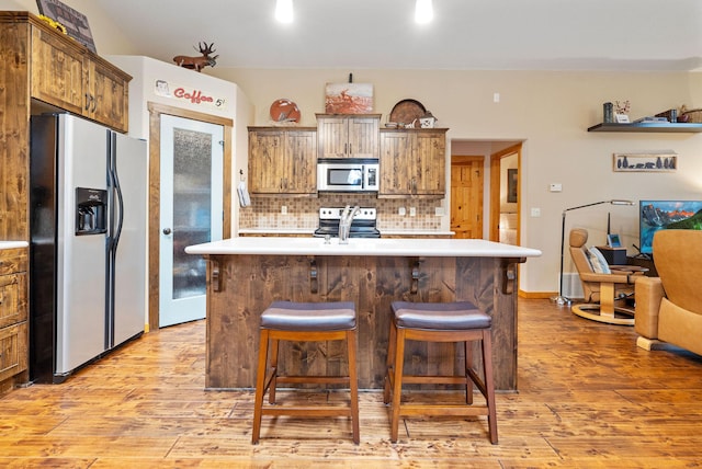 161 Oakmont Loop, Columbia Falls, MT 59912 - kitchen with stainless steel appliances, light wood finished floors, decorative backsplash, light countertops, and a kitchen bar
