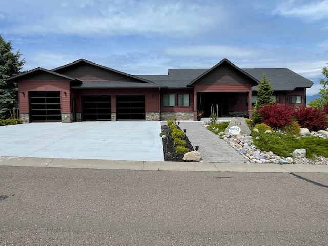 113 Mission Bay Dr, Polson, MT 59860 - view of front of home featuring an attached garage, stone siding, and driveway