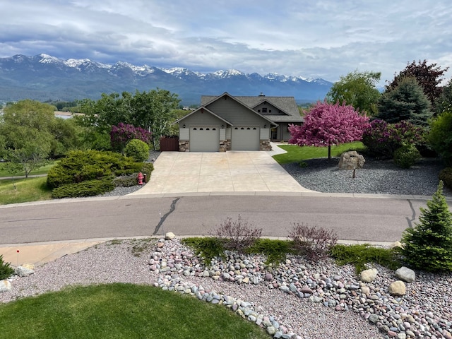 113 Mission Bay Dr, Polson, MT 59860 - view of front facade featuring a mountain view, a garage, concrete driveway, and stone siding