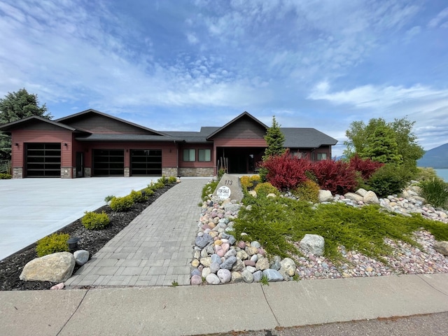 113 Mission Bay Dr, Polson, MT 59860 - view of front of house featuring an attached garage, concrete driveway, and stone siding