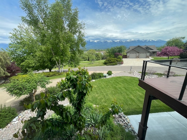 113 Mission Bay Dr, Polson, MT 59860 - view of green lawn with a garage, a deck with mountain view, and concrete driveway