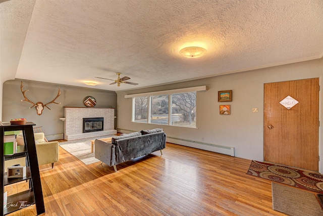 4212 W US Highway 12, Helena, MT 59601 - living area with baseboard heating, ceiling fan, a textured ceiling, hardwood / wood-style floors, and a brick fireplace