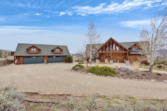 1130 Hegson Dr, Stevensville, MT 59870 - log cabin featuring log siding, a garage, gravel driveway, a shingled roof, and an outbuilding