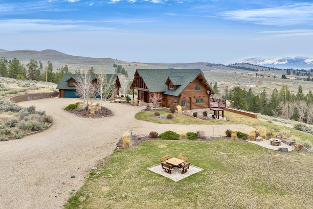 1130 Hegson Dr, Stevensville, MT 59870 - log cabin with a fire pit, log exterior, a mountain view, dirt driveway, and a front yard