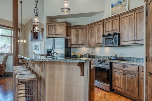 1 Rock Creek Ct, Whitefish, MT 59937 - kitchen with appliances with stainless steel finishes, a breakfast bar, light wood finished floors, brown cabinetry, and a kitchen island