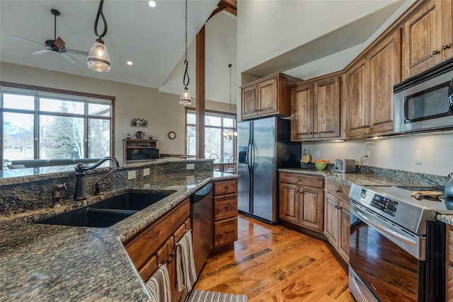 1 Rock Creek Ct, Whitefish, MT 59937 - kitchen with appliances with stainless steel finishes, a sink, light wood finished floors, ceiling fan, and dark stone counters