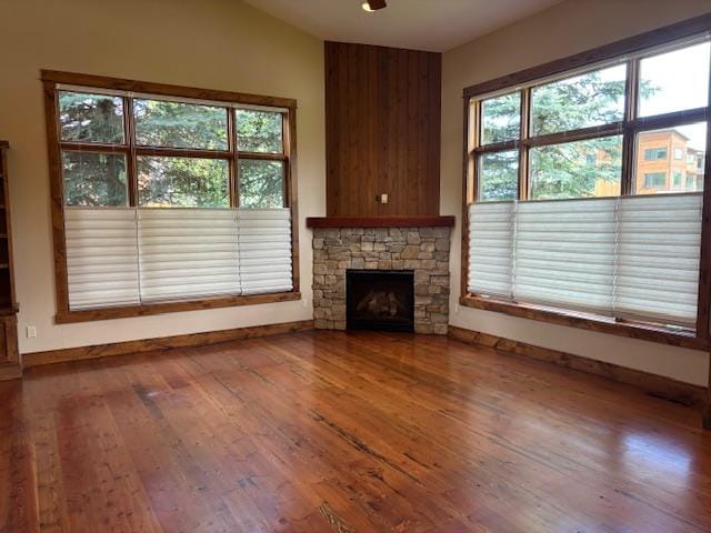 1 Rock Creek Ct, Whitefish, MT 59937 - unfurnished living room featuring hardwood / wood-style flooring, vaulted ceiling, a fireplace, and healthy amount of natural light