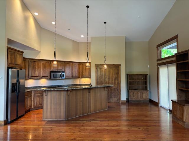 1 Rock Creek Ct, Whitefish, MT 59937 - kitchen with high vaulted ceiling, appliances with stainless steel finishes, dark wood-type flooring, hanging light fixtures, and open shelves
