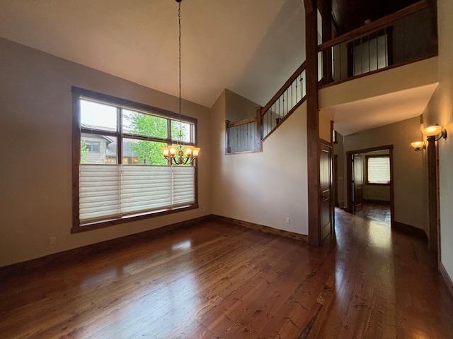1 Rock Creek Ct, Whitefish, MT 59937 - unfurnished dining area featuring a chandelier, high vaulted ceiling, and dark wood finished floors
