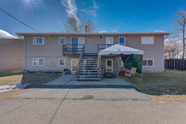 view of front of home featuring stairs, a front yard, a patio area, a deck, and fence