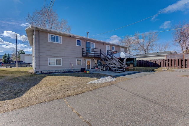 back of property with fence, stairs, and a lawn