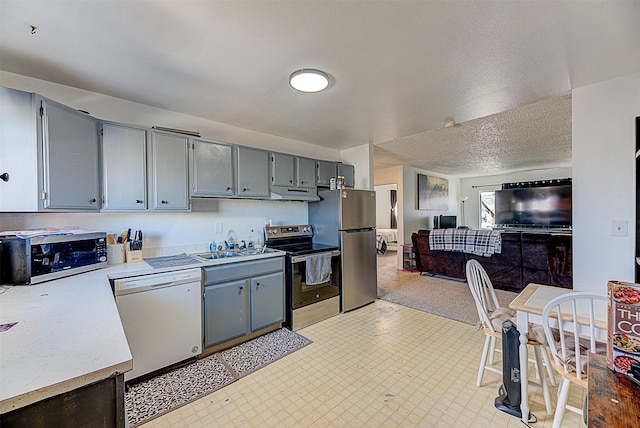 kitchen featuring gray cabinetry, light countertops, under cabinet range hood, and appliances with stainless steel finishes