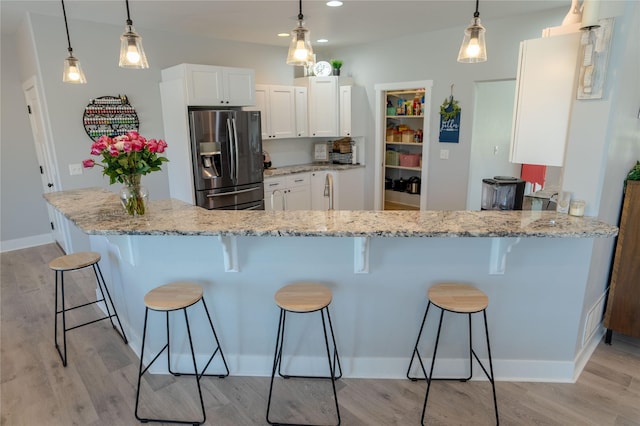 9 Ridge View Cir, Montana City, MT 59634 - kitchen with stainless steel fridge with ice dispenser, a kitchen bar, white cabinetry, light wood-type flooring, and recessed lighting