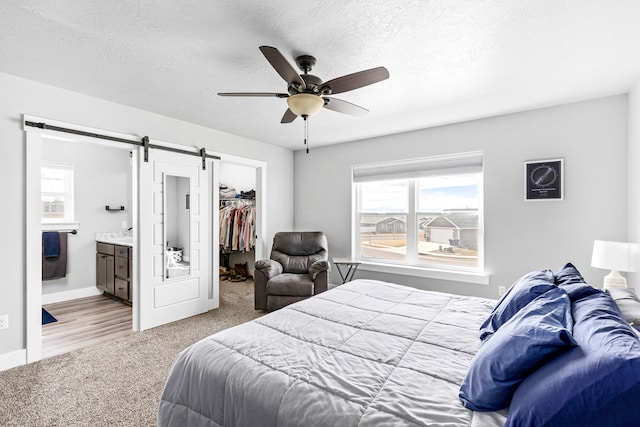 2009 Meriwether Ct, Great Falls, MT 59405 - carpeted bedroom with ensuite bathroom, a barn door, a textured ceiling, and a spacious closet
