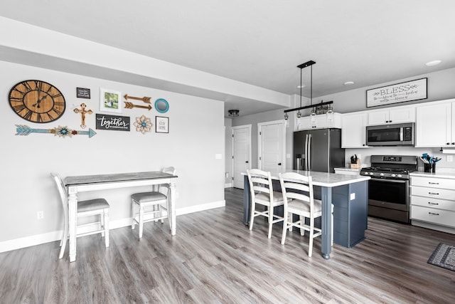 2009 Meriwether Ct, Great Falls, MT 59405 - kitchen featuring wood finished floors, a kitchen island, appliances with stainless steel finishes, white cabinetry, and a breakfast bar area