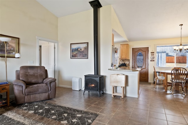 552 Pat Ln, Stevensville, MT 59870 - living room featuring tile patterned floors, high vaulted ceiling, a chandelier, a wood stove, and baseboards