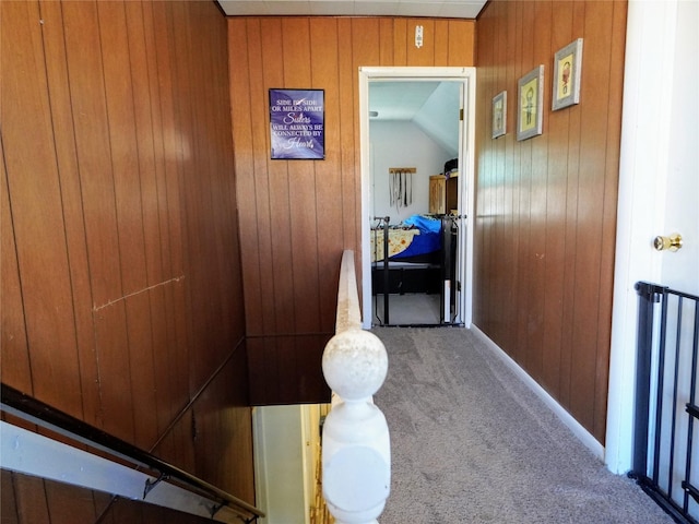 hallway featuring wooden walls and carpet floors