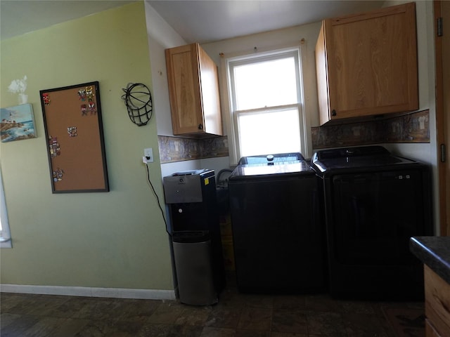 clothes washing area featuring baseboards, cabinet space, and washer and dryer