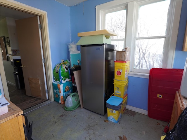 interior space with freestanding refrigerator and unfinished concrete flooring