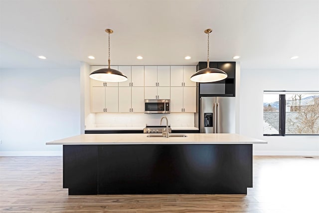2212 S 12th St W, Missoula, MT 59801 - kitchen with a kitchen island with sink, appliances with stainless steel finishes, white cabinetry, a sink, and light wood-type flooring