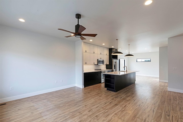 2212 S 12th St W, Missoula, MT 59801 - kitchen featuring light countertops, a center island with sink, appliances with stainless steel finishes, a sink, and light wood-style floors