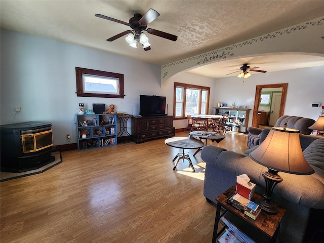 living area featuring a ceiling fan, arched walkways, and a wood stove