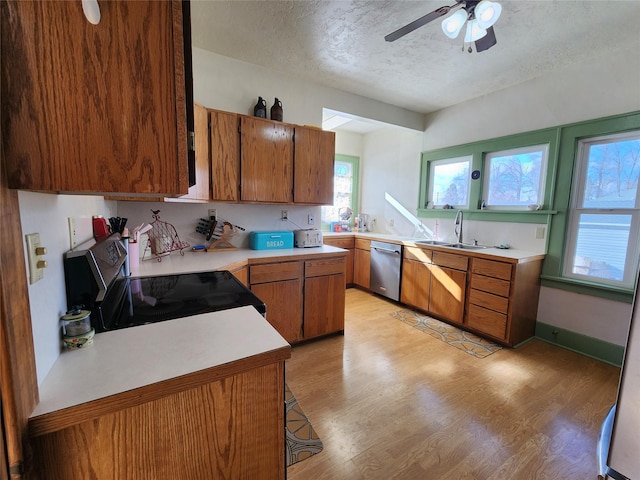 kitchen with a textured ceiling, light countertops, brown cabinets, a ceiling fan, and appliances with stainless steel finishes