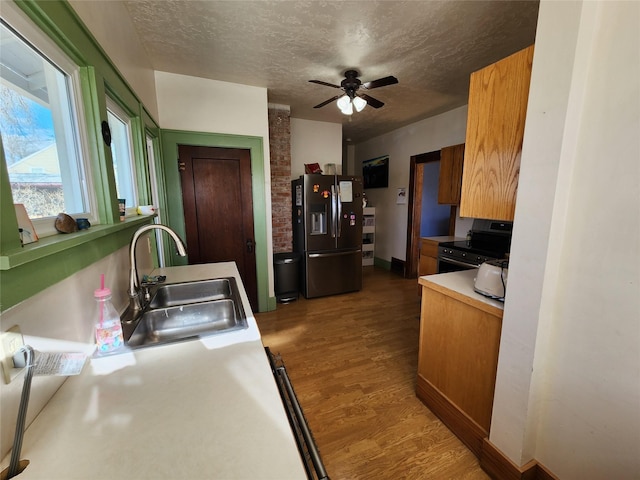 kitchen with wood finished floors, a sink, stainless steel appliances, and a textured ceiling
