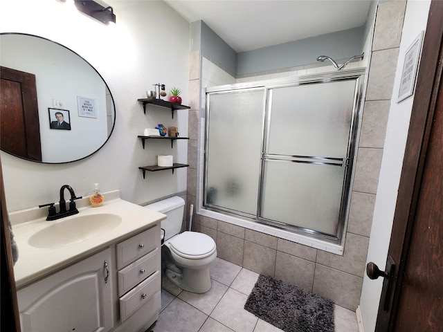 bathroom with tile patterned floors, vanity, tiled shower / bath, and toilet