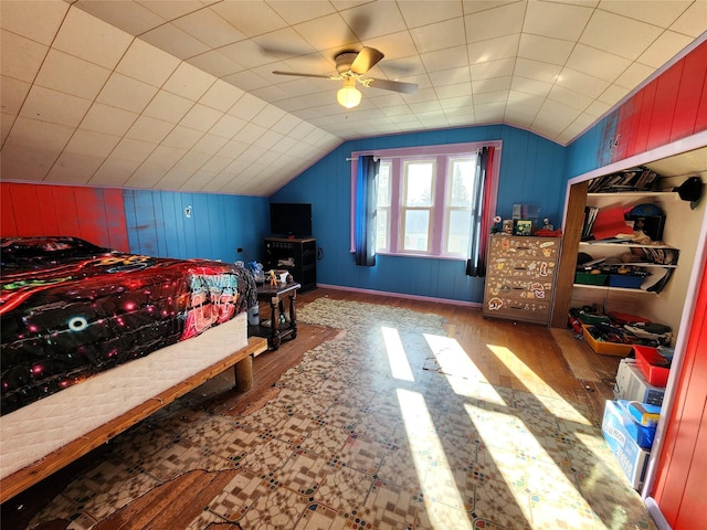 bedroom featuring a ceiling fan, wooden walls, lofted ceiling, and wood finished floors