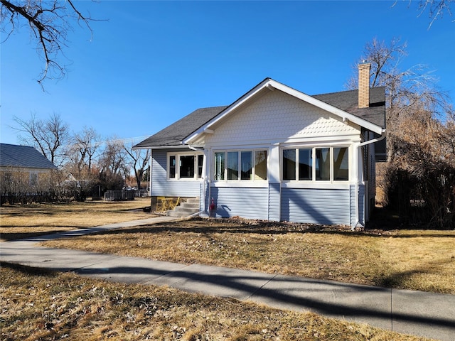 view of front of property with a front yard, entry steps, and a chimney