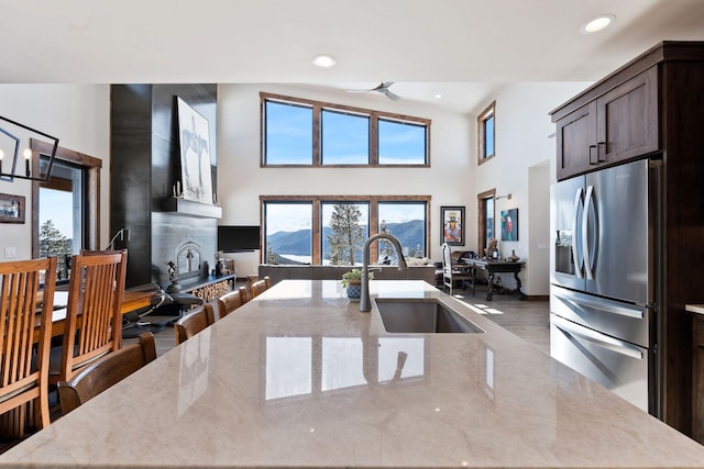 85 Meadows Dr, Whitefish, MT 59937 - kitchen featuring stainless steel refrigerator with ice dispenser, a high ceiling, wood finished floors, a large island with sink, and light stone counters