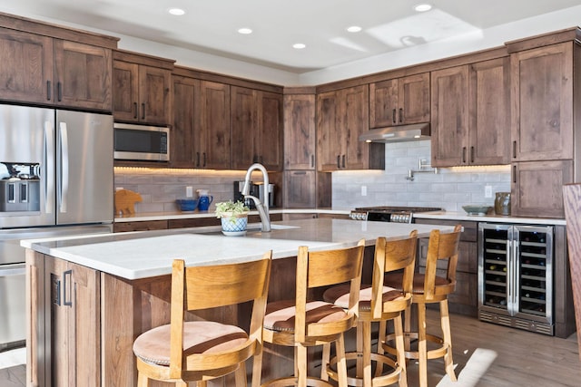 85 Meadows Dr, Whitefish, MT 59937 - kitchen with wine cooler, appliances with stainless steel finishes, decorative backsplash, light countertops, and under cabinet range hood