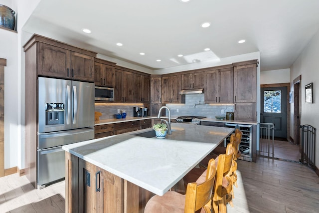 85 Meadows Dr, Whitefish, MT 59937 - kitchen with stainless steel appliances, beverage cooler, light wood-style flooring, recessed lighting, and under cabinet range hood
