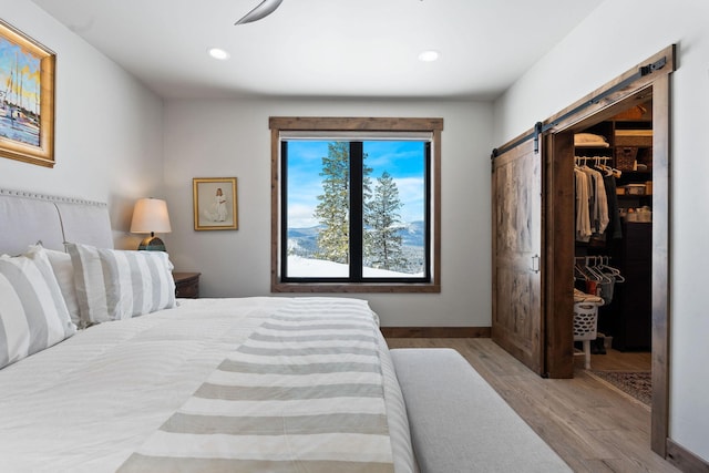 85 Meadows Dr, Whitefish, MT 59937 - bedroom with a barn door, wood finished floors, a walk in closet, recessed lighting, and a closet