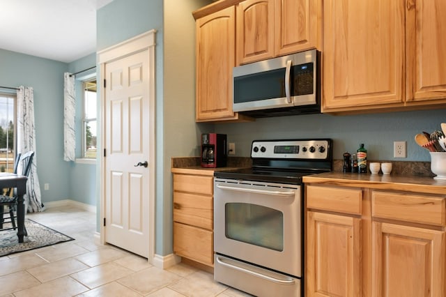 369 Gold Ct, Florence, MT 59833 - kitchen featuring appliances with stainless steel finishes, light brown cabinetry, light tile patterned floors, dark countertops, and baseboards