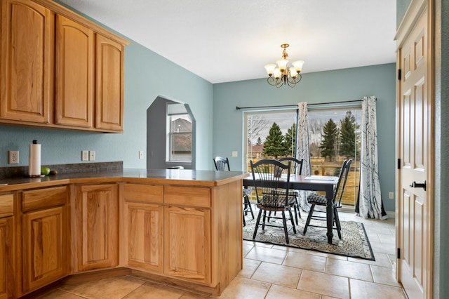 369 Gold Ct, Florence, MT 59833 - kitchen with a chandelier, light tile patterned floors, arched walkways, a peninsula, and dark countertops