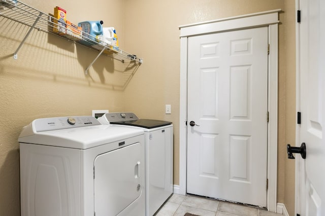 369 Gold Ct, Florence, MT 59833 - laundry area with washing machine and dryer, light tile patterned floors, a textured wall, and baseboards