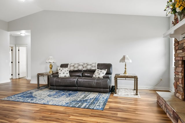 369 Gold Ct, Florence, MT 59833 - living room featuring a fireplace with raised hearth, wood finished floors, vaulted ceiling, and baseboards