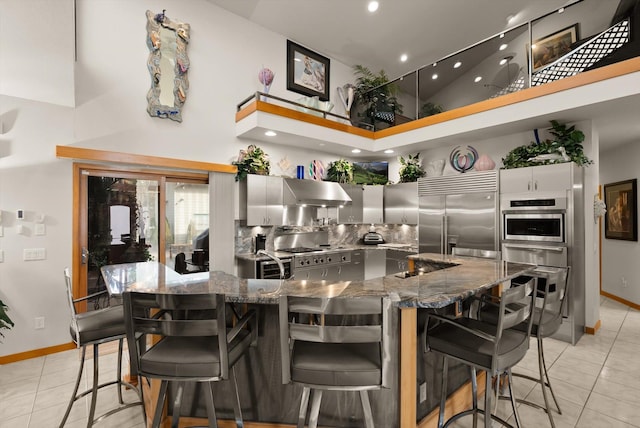 229AND231 Harbor Dr, Bigfork, MT 59911 - kitchen with built in fridge, a towering ceiling, light tile patterned flooring, under cabinet range hood, and dark stone countertops