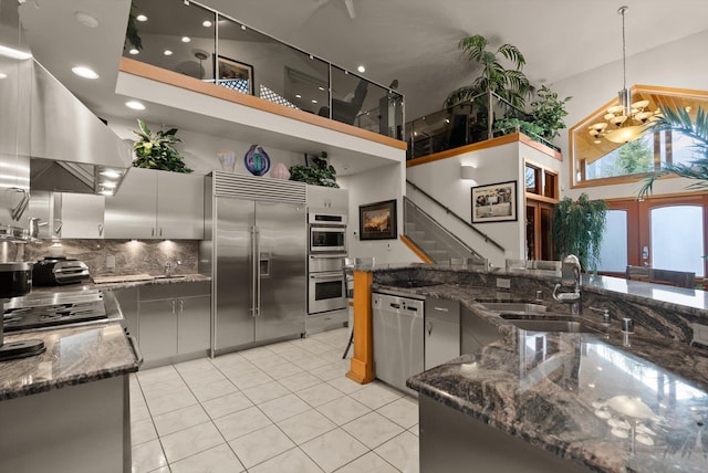 229AND231 Harbor Dr, Bigfork, MT 59911 - kitchen with appliances with stainless steel finishes, a high ceiling, light tile patterned floors, dark stone counters, and backsplash