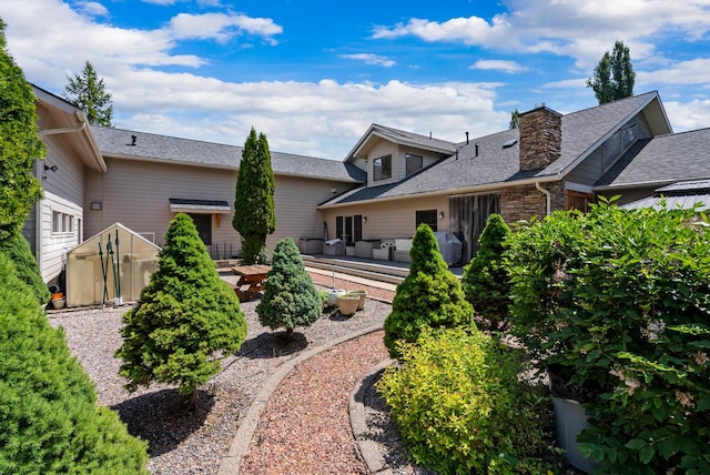229AND231 Harbor Dr, Bigfork, MT 59911 - back of house featuring a patio, a shingled roof, an outdoor living space, and a chimney