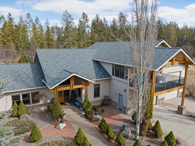 229AND231 Harbor Dr, Bigfork, MT 59911 - view of front of house featuring roof with shingles, stone siding, and driveway