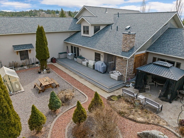 229AND231 Harbor Dr, Bigfork, MT 59911 - rear view of property featuring a gazebo, a deck, a shingled roof, an outdoor hangout area, and stone siding