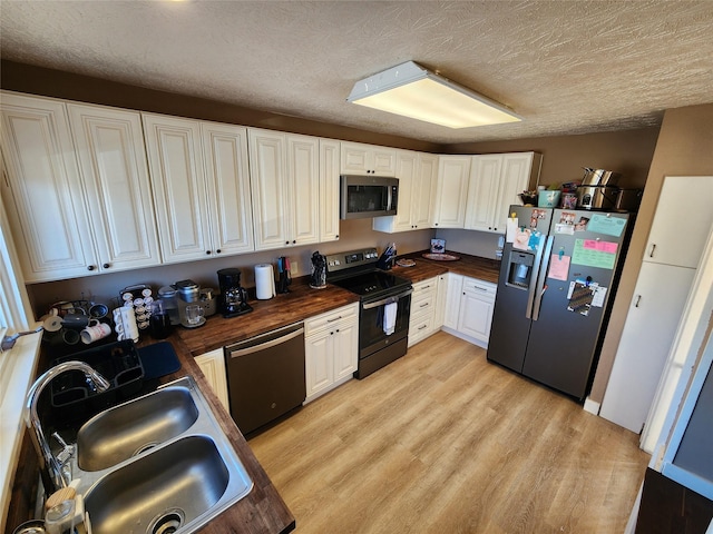 3301 1st Ave N, Great Falls, MT 59401 - kitchen with appliances with stainless steel finishes, butcher block counters, light wood-style floors, white cabinetry, and a textured ceiling