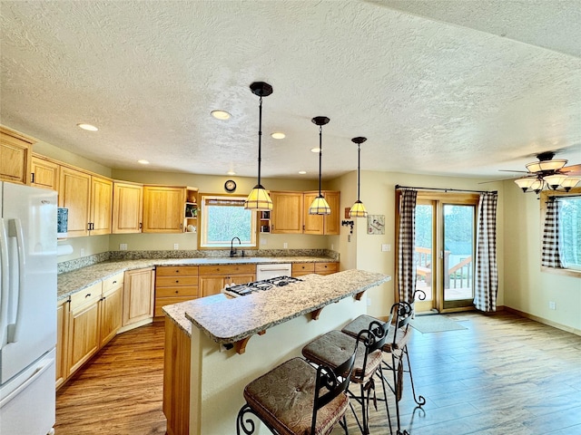 19066 King Rd, Florence, MT 59833 - kitchen featuring white appliances, light wood finished floors, recessed lighting, a textured ceiling, and a kitchen breakfast bar