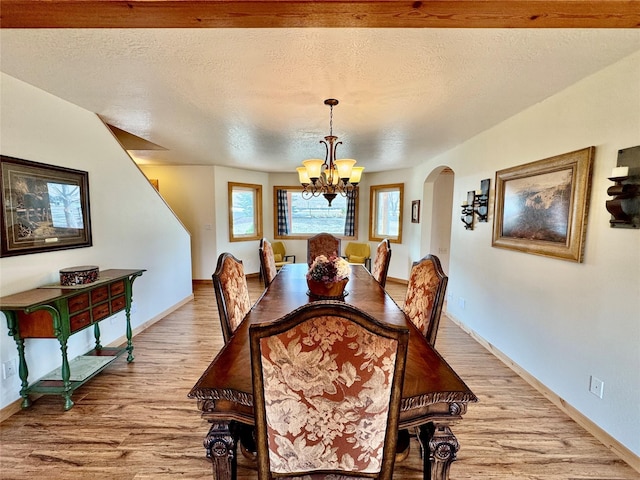 19066 King Rd, Florence, MT 59833 - dining room featuring a chandelier, a textured ceiling, light wood-type flooring, baseboards, and arched walkways