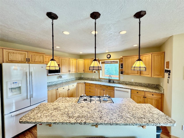 19066 King Rd, Florence, MT 59833 - kitchen with decorative light fixtures, recessed lighting, white appliances, a kitchen island, and light stone countertops