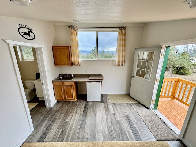 19066 King Rd, Florence, MT 59833 - kitchen featuring white dishwasher, brown cabinetry, light wood-style flooring, and a sink